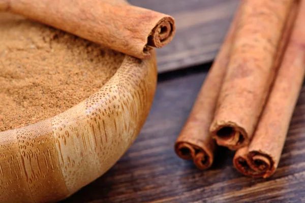 Polvo de canela en un tazón de bambú con palitos de canela — Foto de Stock