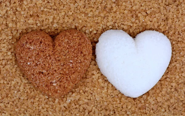 Бежевое сердце сахара с белым сердцем сахара на фоне сахара — стоковое фото