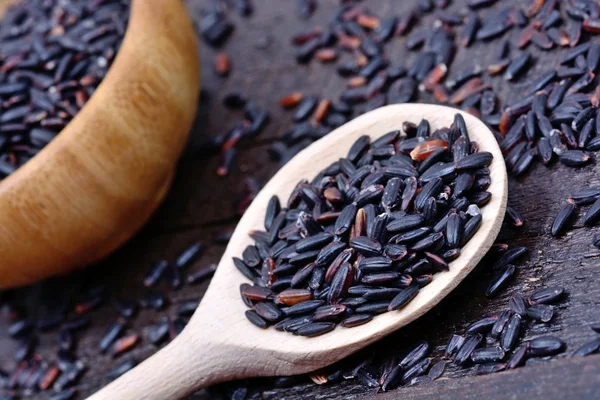 Black rice in a wooden spoon and bowl
