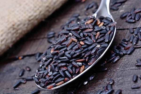 Black rice in a metal spoon on table — Stock Photo, Image