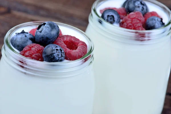 Gläser mit Joghurt und verschiedenen Beeren auf dem Tisch — Stockfoto