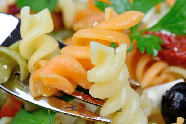 Vidlice s barevné těstoviny a olivový, sýrem a petrželkou — Stock fotografie