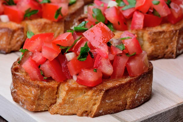 Bruschetta with tomatoes and garlic on chopping wooden board — Free Stock Photo