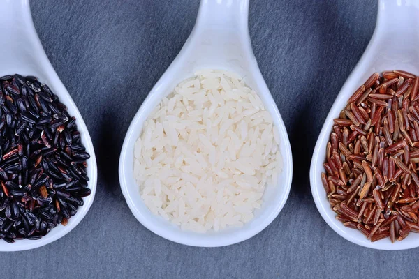 Různé typy rýže v keramické lžičky — Stock fotografie