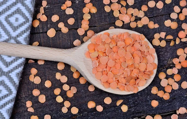 Colher de madeira com lentilhas vermelhas na mesa — Fotografia de Stock