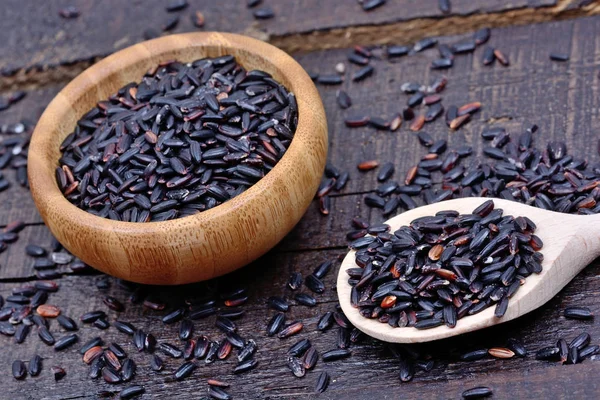 Black rice in a wooden spoon and bowl — Stock Photo, Image