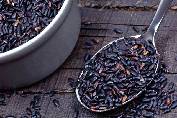 Black rice in a spoon and pot on table — Stock Photo, Image