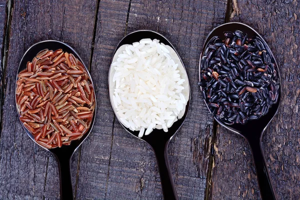 Kovové lžíce s rýží na stole — Stock fotografie