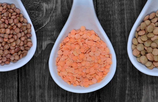 Diferentes tipos de lentilhas em uma colher de cerâmica — Fotografia de Stock