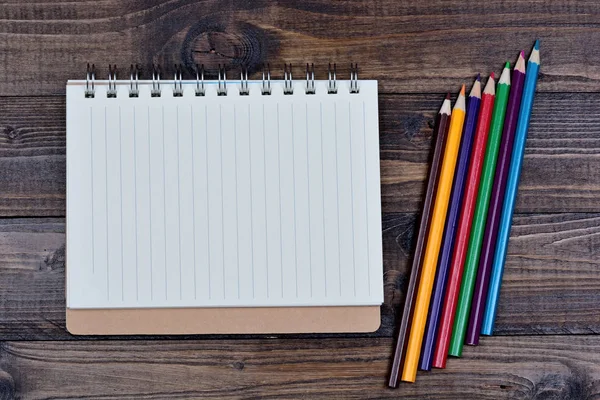 Caderno com lápis coloridos na mesa — Fotografia de Stock
