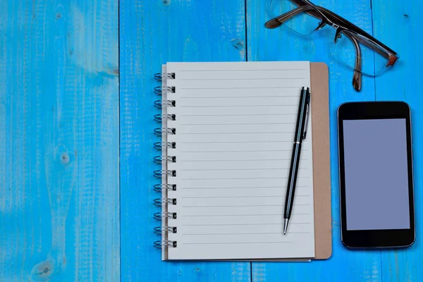 Notebook z telefon i okulary na stole — Zdjęcie stockowe