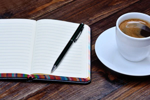 Bloc de notas con pluma y taza de café en la mesa — Foto de Stock