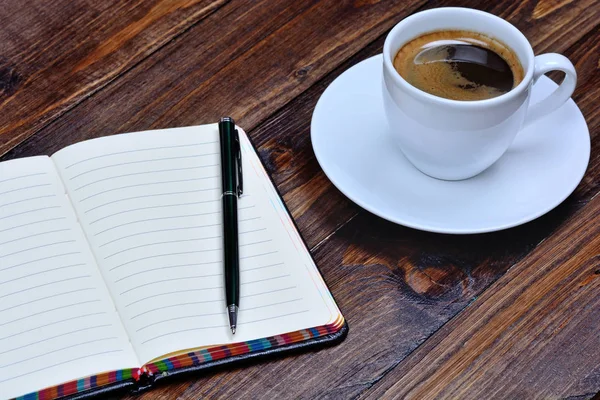 Notebook s kávou na dřevěný stůl — Stock fotografie