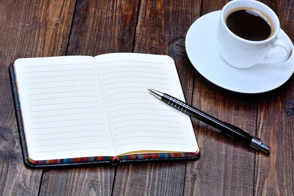 Caderno com caneta e xícara de café na mesa — Fotografia de Stock