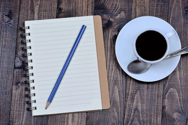 Ahşap arka plan üzerinde kalem ve kahve Kupası ile not etmek — Stok fotoğraf
