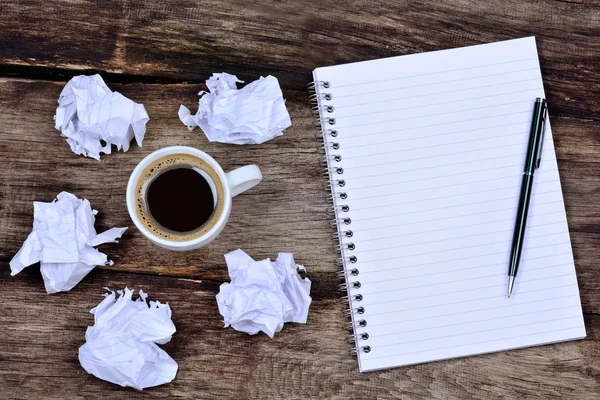 Bloco de notas com café caneta e papel amassado na mesa — Fotografia de Stock