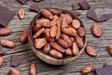 Masada koyu çikolata ile bir kase içinde kakao çekirdekleri