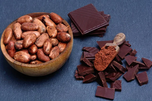Kakao bönor i en skål med choklad på skiffer — Stockfoto