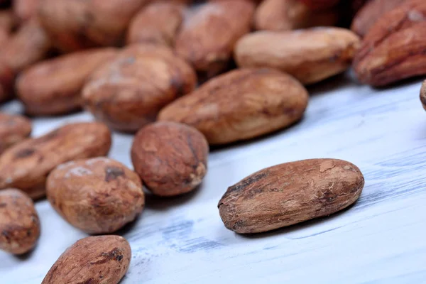 Många kakaobönor på vitt bord — Stockfoto