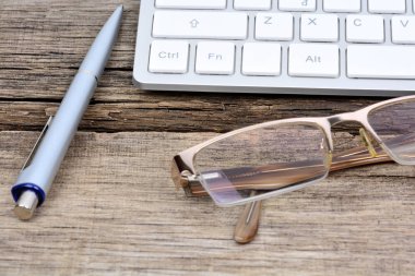 Klavye bilgisayar ve kalem masada gözlük