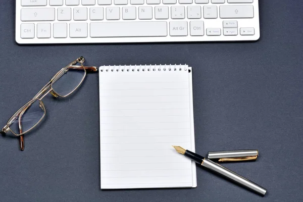 Notizblock mit Füllfederhalter, Brille und Tastatur — Stockfoto