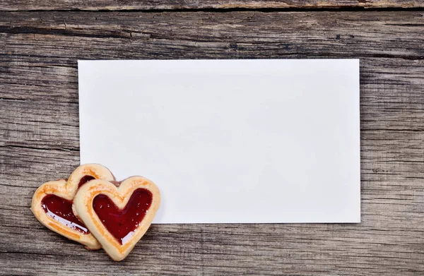 Empty paper with heart cookies on wooden background — Stock Photo, Image