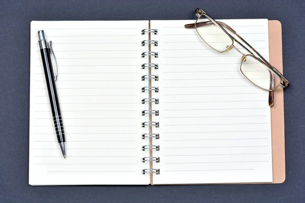 Mesa de escritorio de oficina con papel cuaderno abierto, bolígrafo y anteojos —  Fotos de Stock