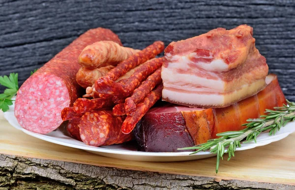 Вкусный копченый бекон, сосиски, крудо с ветчиной и салями на тарелке — стоковое фото