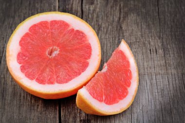 Yarım ve ahşap masa üzerinde kırmızı greyfurt parçası