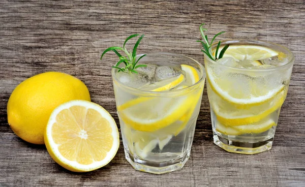 Wasser mit frischer Zitrone und Rosmarin auf Holzgrund — Stockfoto