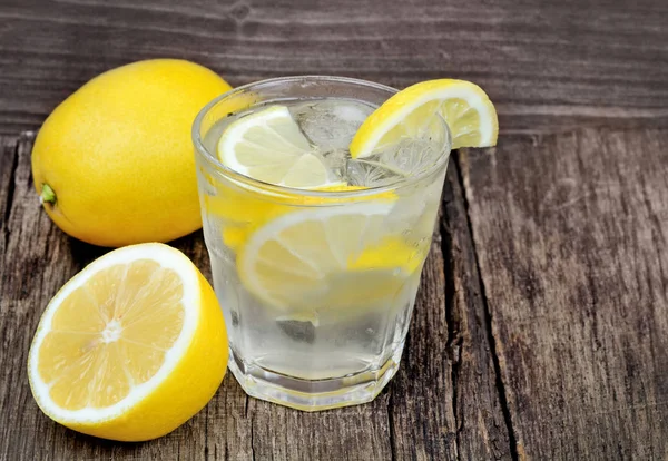 Entgiftungswasser mit Zitrone und Eiswürfeln in einem Glas auf Holztisch — Stockfoto