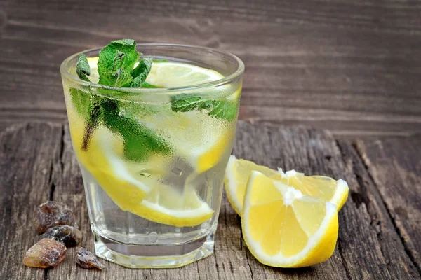 Wasser mit Zitrone und Minze in einem Glas auf Holzgrund — Stockfoto
