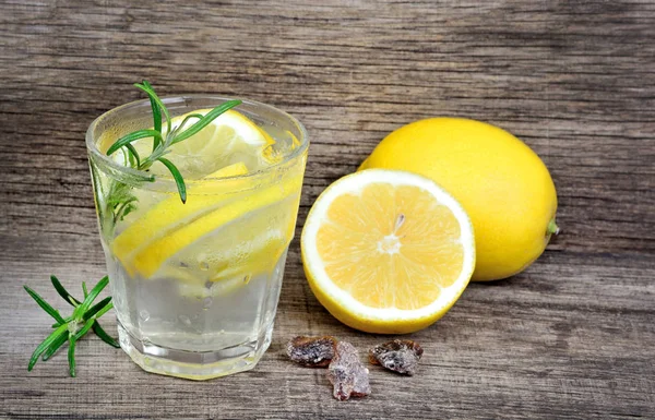 Wasser mit Zitrone und Rosmarin im Glas auf altem Tisch — Stockfoto