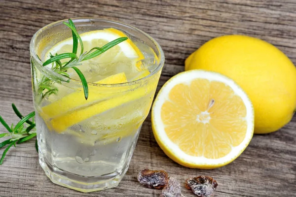 Leckeres kühles Getränk mit Zitrone und Rosmarin auf Holztisch — Stockfoto