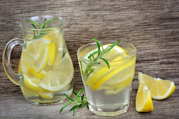 Zitronenwasser mit Rosmarin und Eiswürfeln im Glas und Krug — Stockfoto