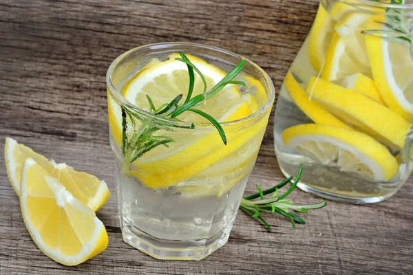 Limon ve biberiye ahşap masa üzerinde bir bardak suda detoks. Soğuk Yaz içeceği yenileniyor — Stok fotoğraf