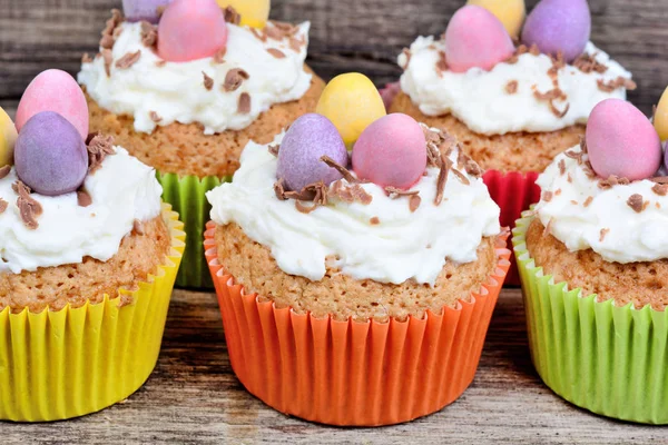 Paskalya yumurtaları ve ahşap arka plan üzerinde buzlanma ile küçük Paskalya cupcakes — Stok fotoğraf
