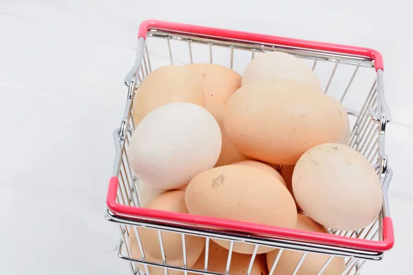 Grupo de huevos en un carrito de la compra en una mesa de madera — Foto de Stock