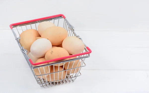Tumpukan telur di keranjang belanja di atas meja kayu — Stok Foto