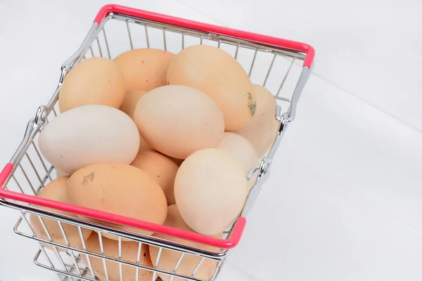 Banyak telur di keranjang belanja di atas meja kayu — Stok Foto
