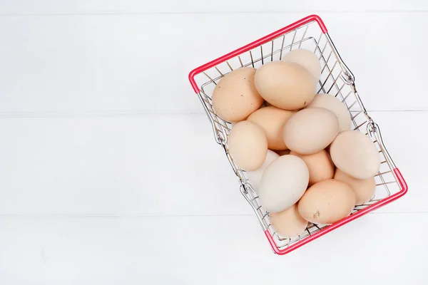 Muchos huevos en un carrito de la compra en una mesa de madera — Foto de Stock