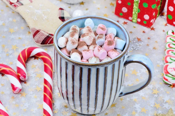 Renkli şekerlemeli bir kupada sıcak çikolata ve masada Noel süsü. — Stok fotoğraf
