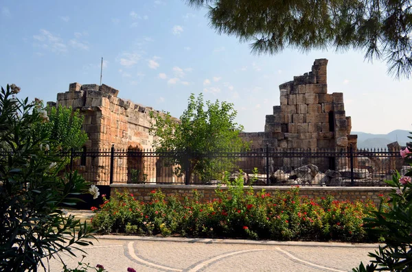 Güneşli bir günde bitkiler ve çiçeklerle güzel bir cadde, Türkiye 'de tarihi bir binanın kalıntıları.