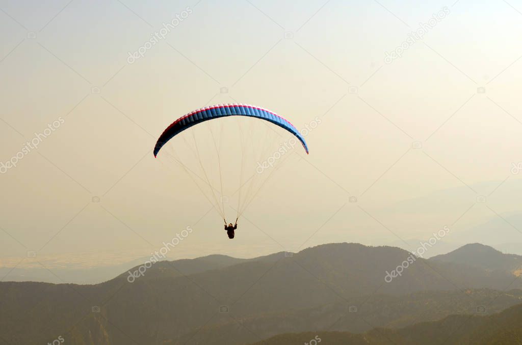 Paragliding flying in the sky over the mountains and the sea (tandem). View from Tahtali mountain, Turkey. Extreme sport. Landscape
