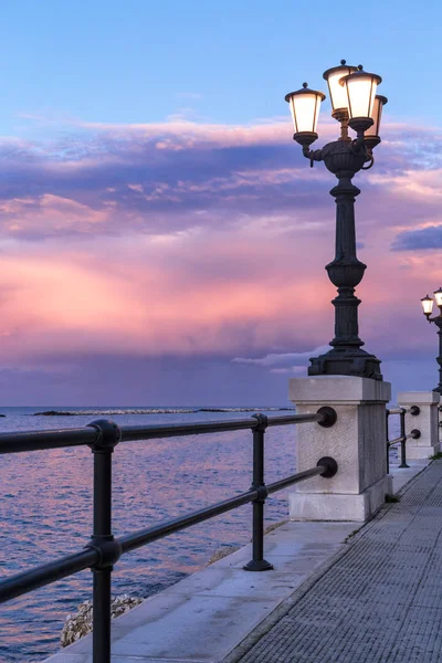 Bari à beira-mar ao pôr-do-sol. Lâmpada de rua original antiga , Fotografia De Stock