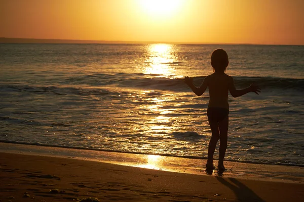 Boy playing on beach at sunset — Stock Photo, Image