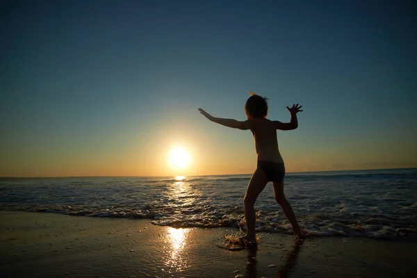Menino brincando na praia ao pôr do sol — Fotografia de Stock