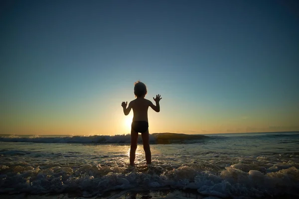 Fiú játszik tengerparton naplementekor — Stock Fotó