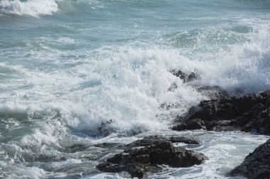 Dalgalar sıçramalarına kayalık kıyısında