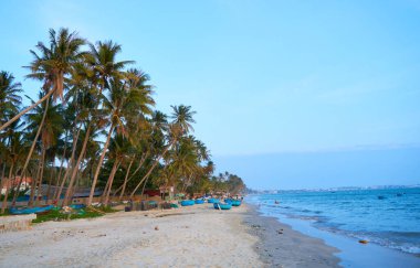 Gün batımından önce deniz kıyısında mavi botlar